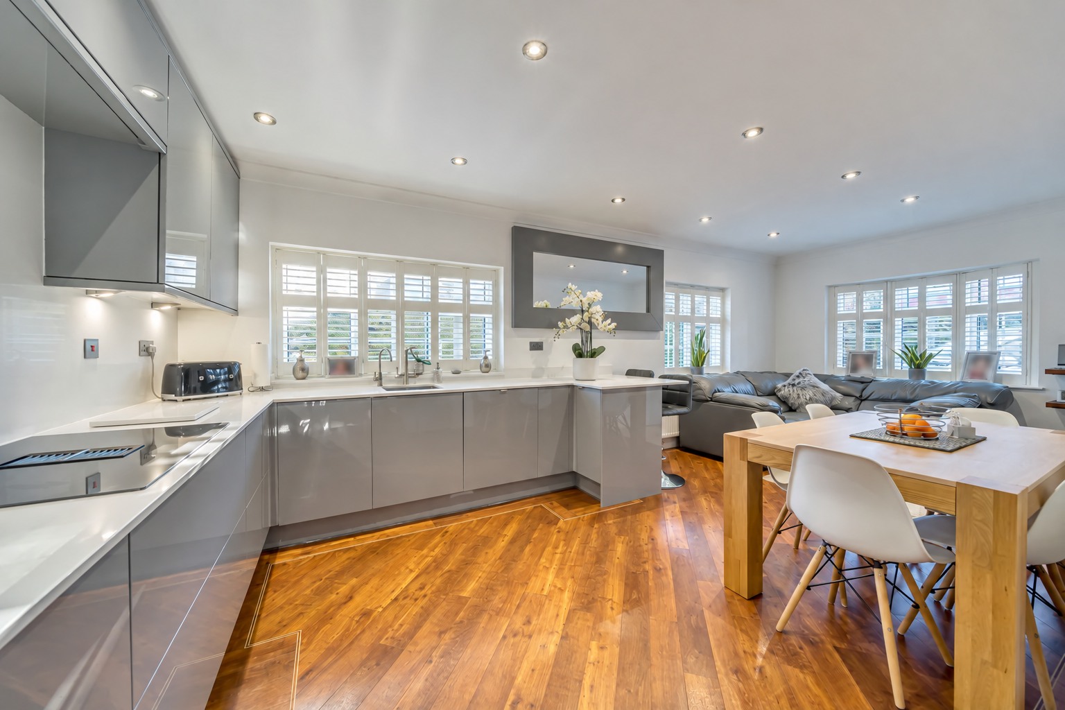 Grey kitchen with white worktops, timber flooring and an adjoining dining and living area